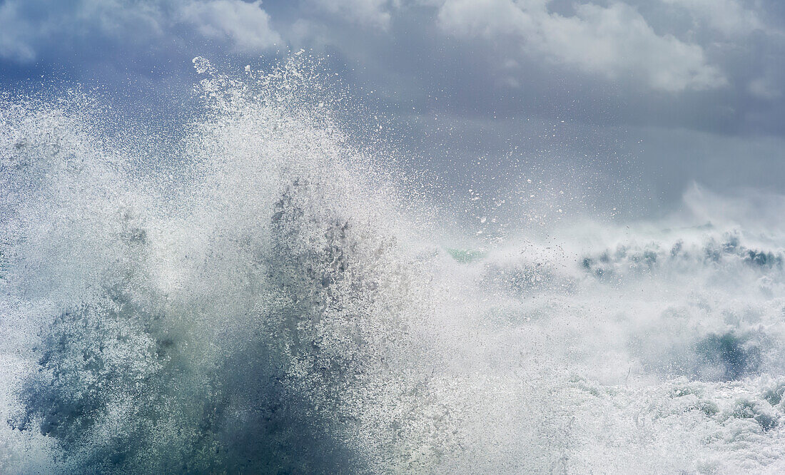 Wellen kräuseln sich und brechen während des Zyklons Ola mit stürmischem Himmel