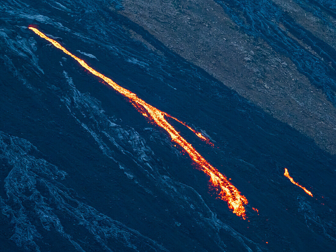 Glühende Lavakaskade, die aus der Lavaröhre des Vulkans Fagradalsfjall, Island, verschüttet wird