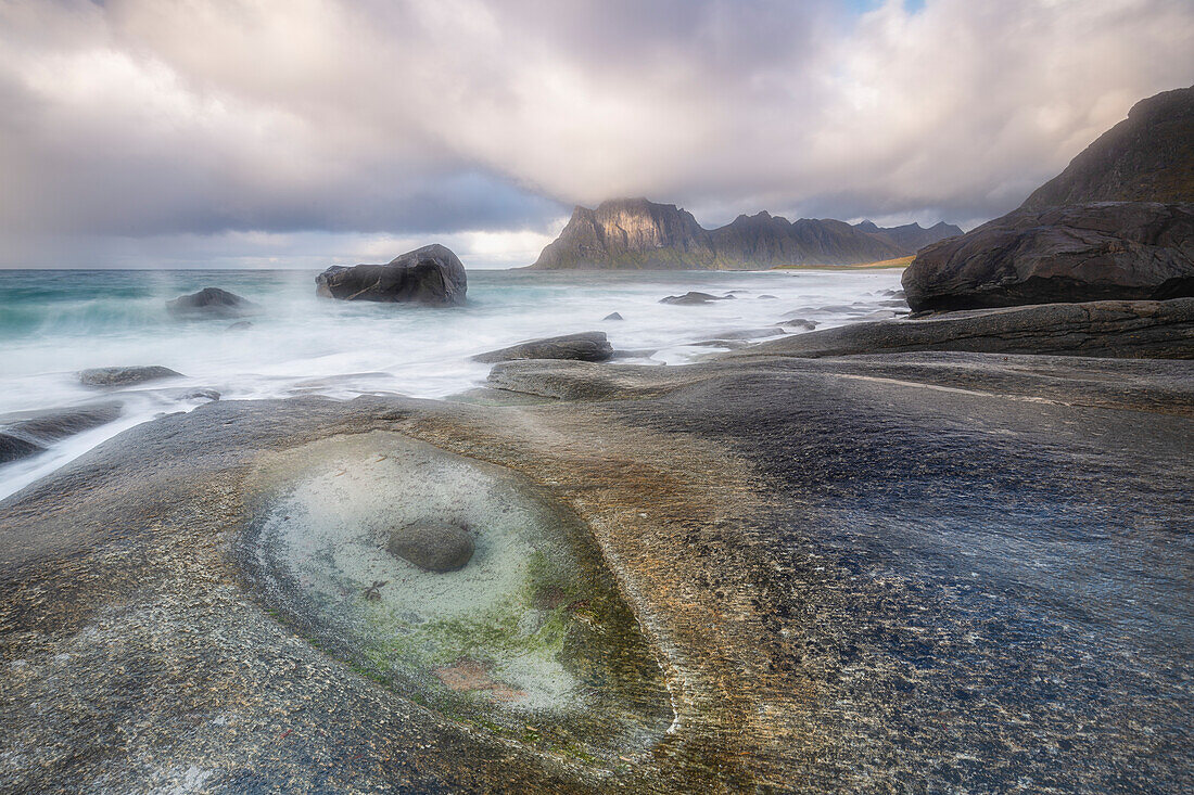Rocky coast with tide pools. Mountains in the background.Uttakleiv, Leknes, Lofoten, Norway.