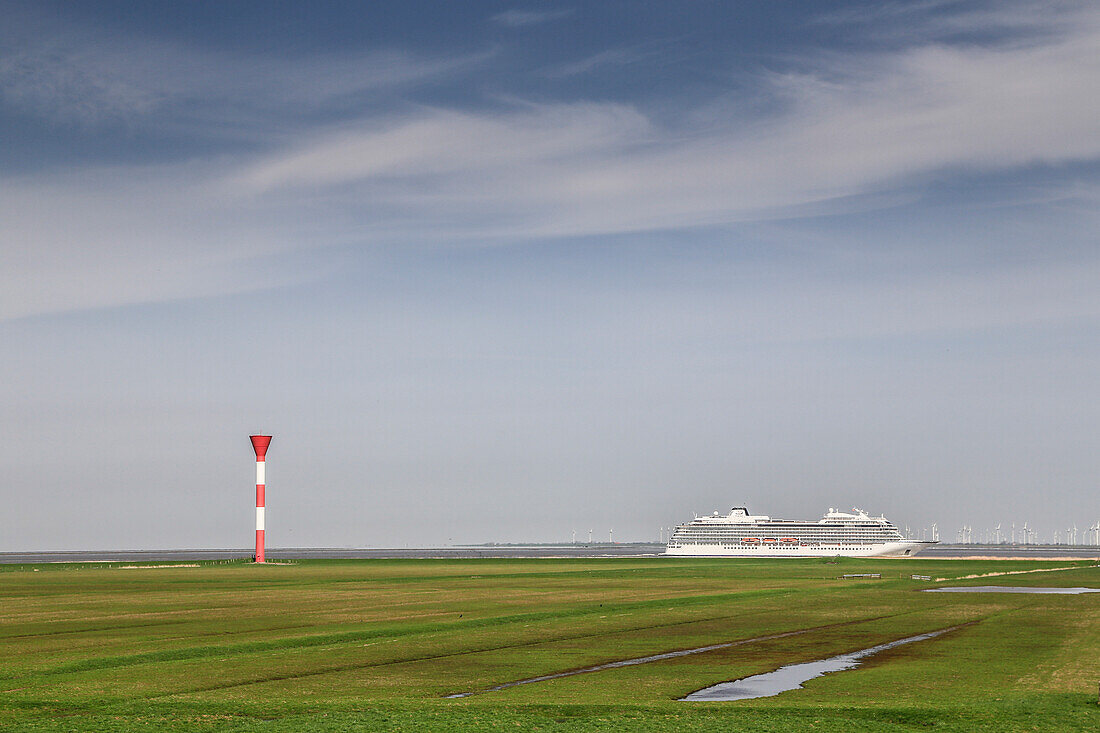 Cruise ship and sea mark on the Elbe. Meadows in the foreground.