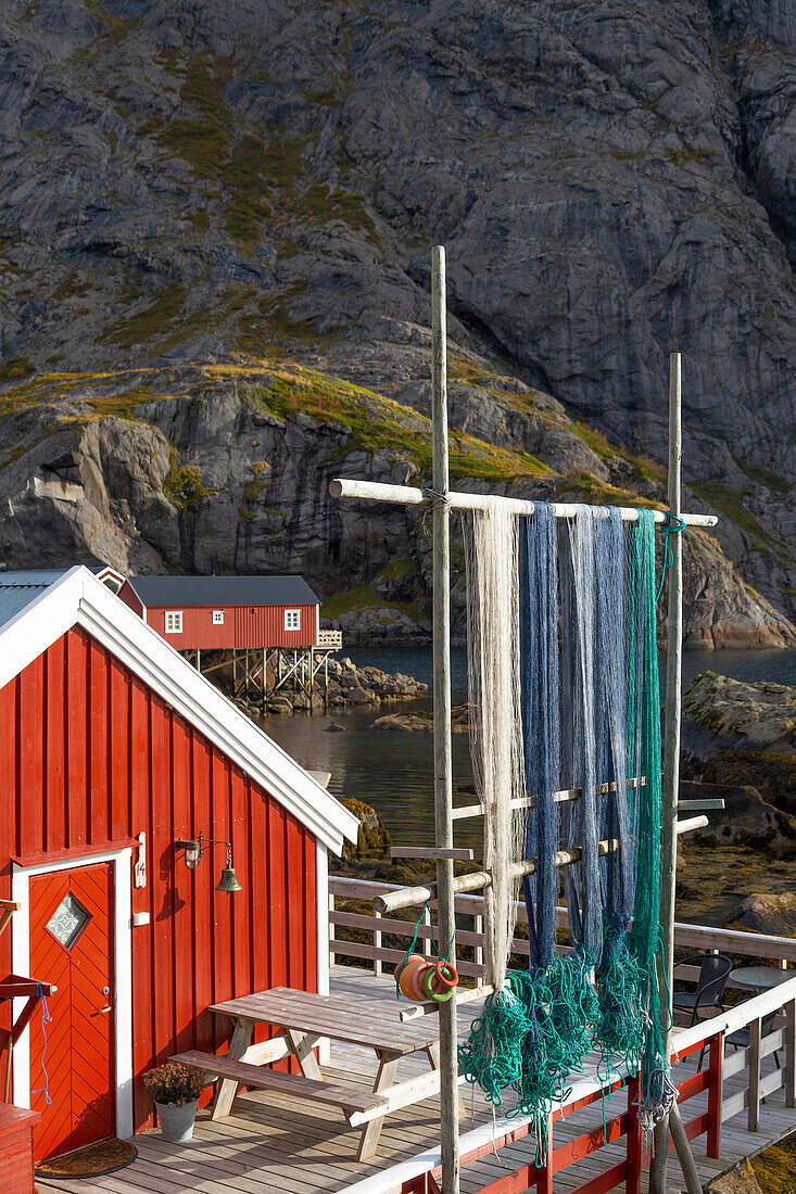 Rote Hütte mit Fischernetzen am Fjord, Nusfjord, Flakstad, Lofoten, Norwegen.