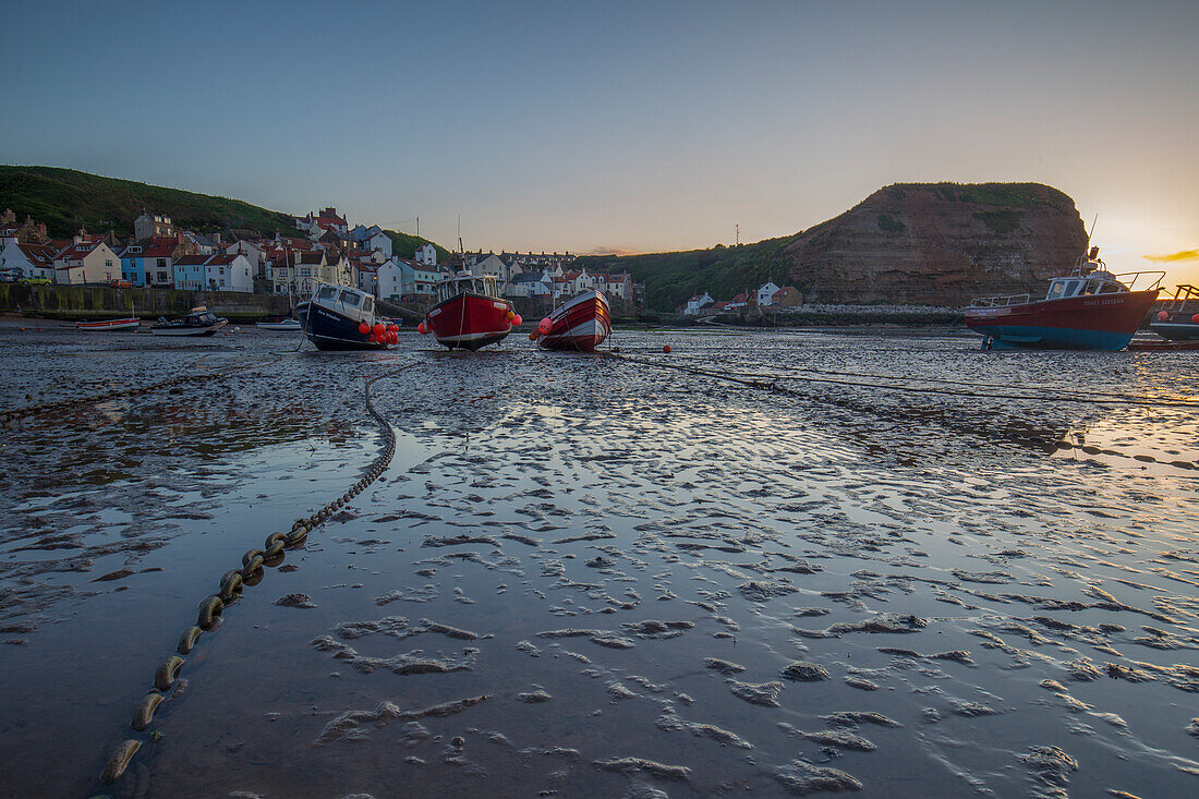 Fishing boats on chain, dried up off Staithes harbour, England.