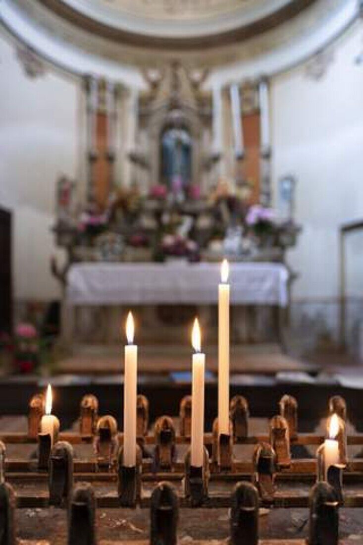 Sacrificial candles and altar with the image of Mary out of focus in the background, Casalmaggiore, Cremona Province, Italy, Europe