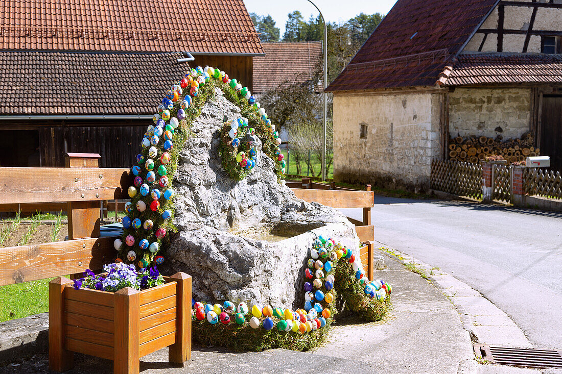 Tufa fountain decorated with colorful Easter eggs in Zoggendorf in Franconian Switzerland, Bavaria, Germany