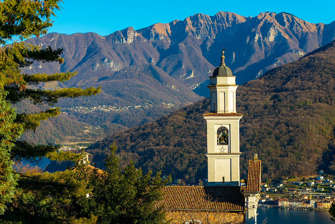 Kirche der Heiligen Fedele und Simone und Luganersee mit Berg an einem sonnigen Tag in Vico Morcote, Tessin in der Schweiz