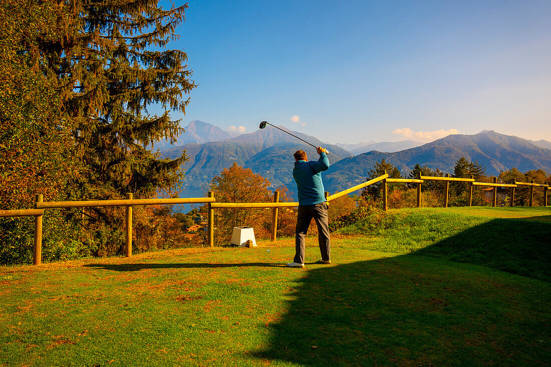 Golfer Abschlag auf dem Golfplatz Menaggio mit Blick auf die Berge im Herbst in der Lombardei, Italien