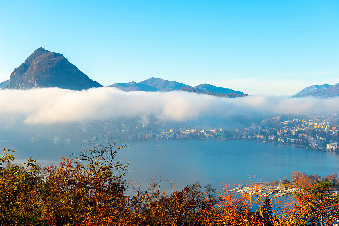 Mountain Peak San Salvatore Above Cloudscape and Lake Lugano with Sunlight and Clear Sky in City of Lugano, Ticino in Switzerland.