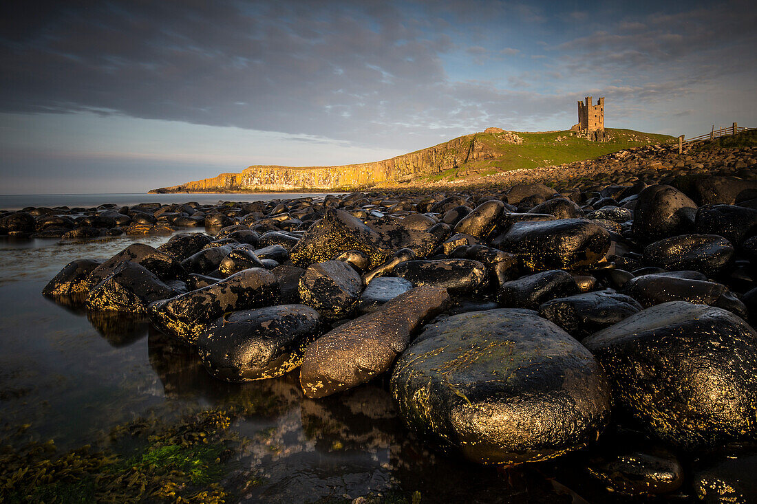 View of the stone coast at Dunstanburgh Castle ruins, Northumberland, England, Great Britain, sunset,