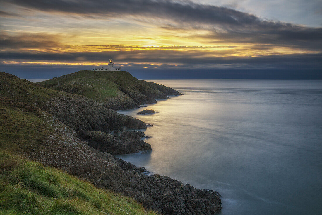 View along the coast towards sunset at Strumble Head Lighthouse in Trefasser, Wales, UK.
