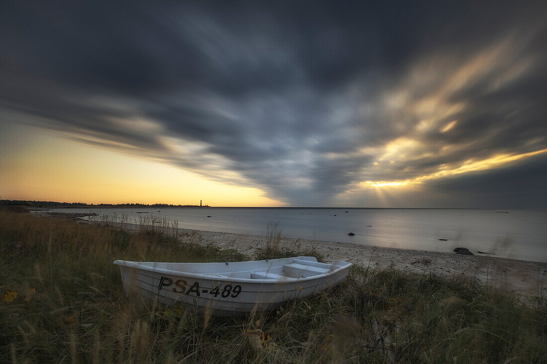Ruderboot am Strand von Matsi, Pärnu, Estland, Baltikum, Ostsee. Dunkle Wolken, Sonnenstrahlen.