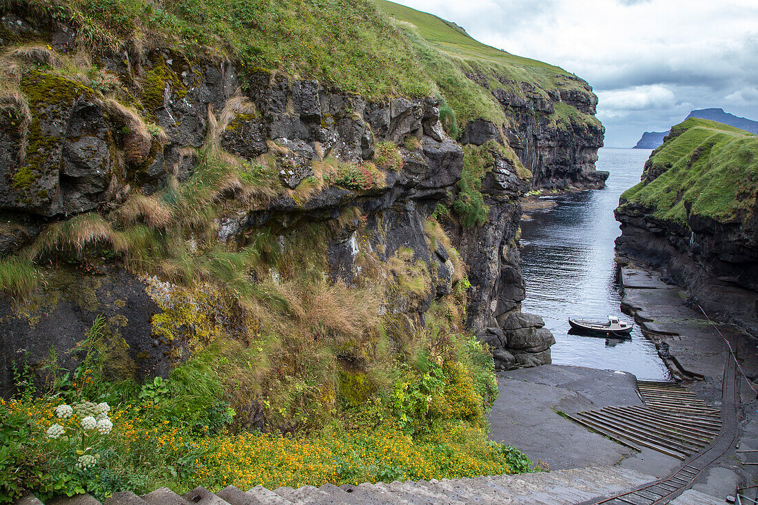 Looking down into small port of Gjogv. Stairs in the foreground, fishing boat. Eysturoy, Faroe Islands.