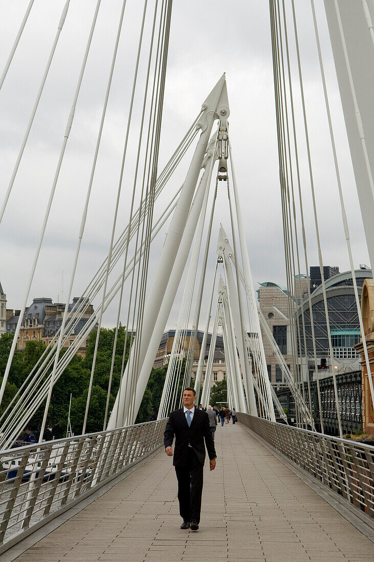 Businessman walking over Jubilee Footbridge next to Cannon St Railway Bridge, London, UK