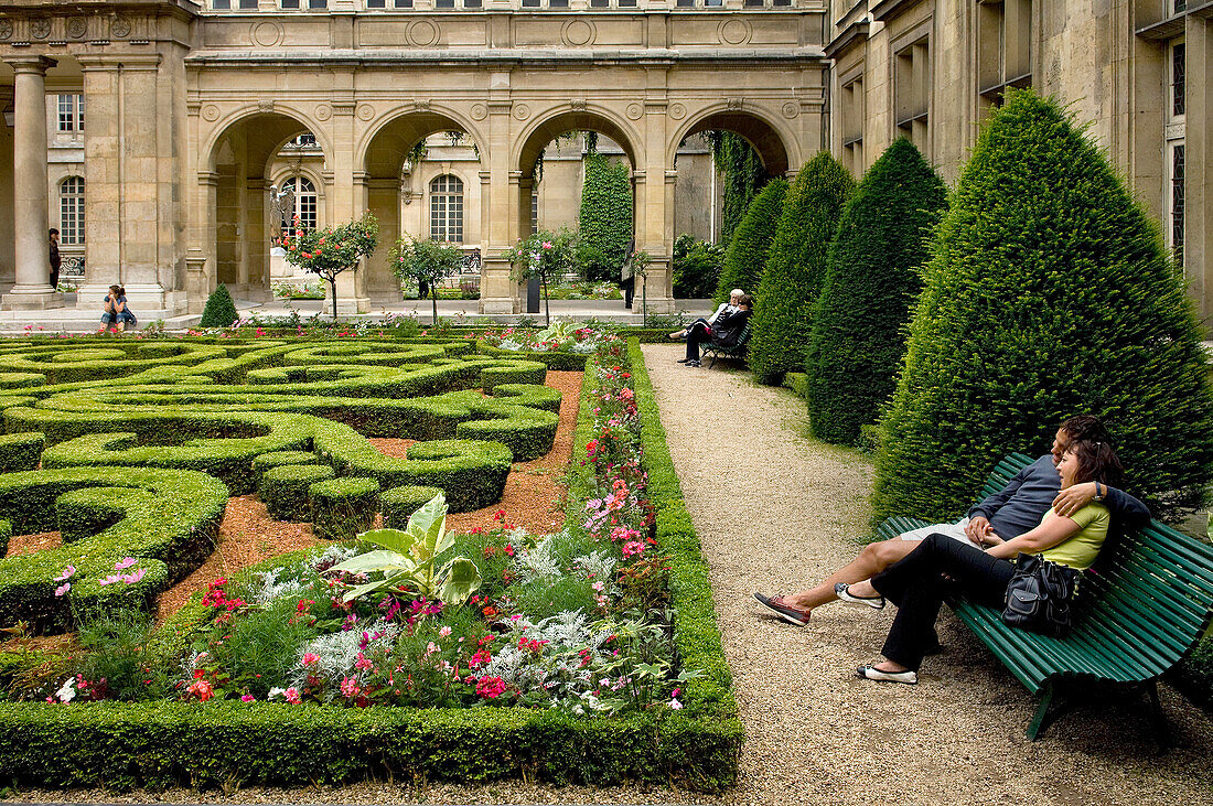 Couple sitting on a bench in the gardens at the Musee Carnavalet ,Marais, Paris, France