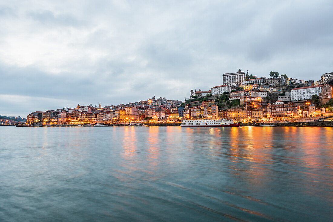 Nachtaufnahme der Uferpromenade Cais de Ribeira und der historischen Altstadt von Porto, Portugal