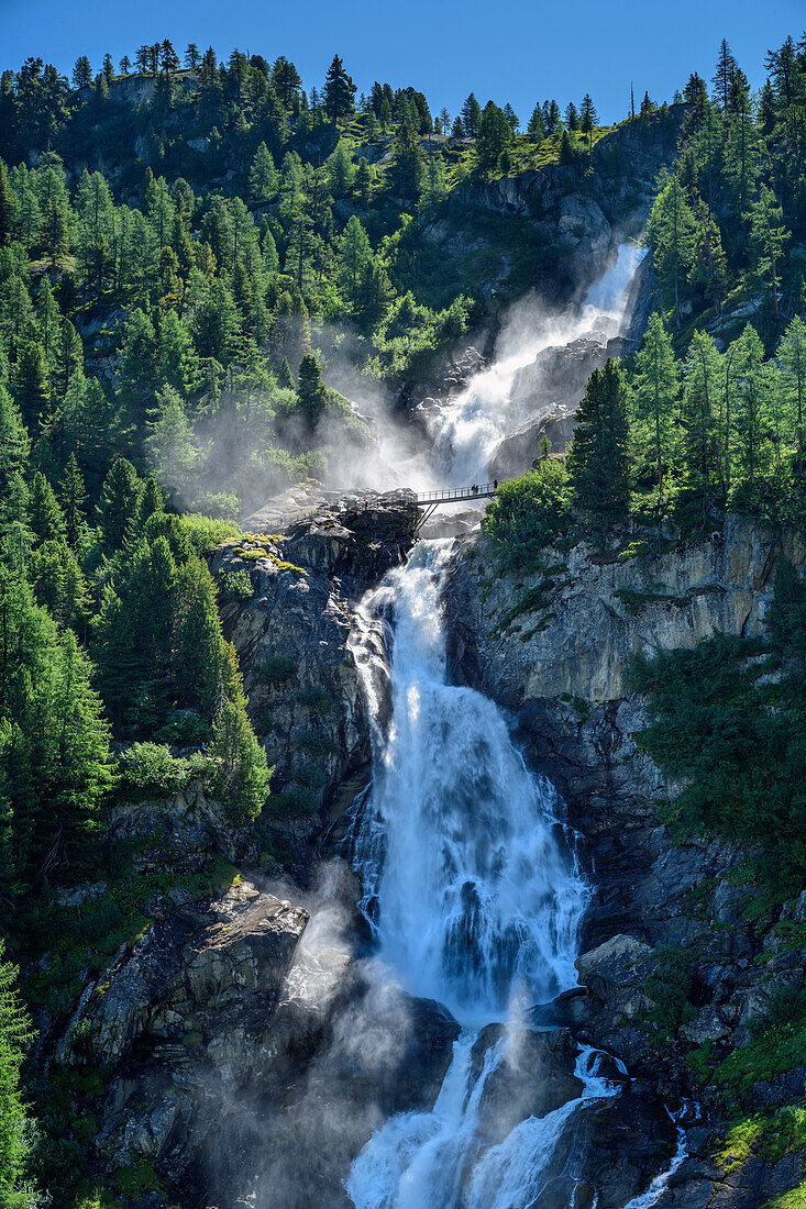 Personen stehen auf Brücke vor Rutor-Wasserfällen, Rutorfälle, Rutorgruppe, Grajische Alpen, Aosta, Italien