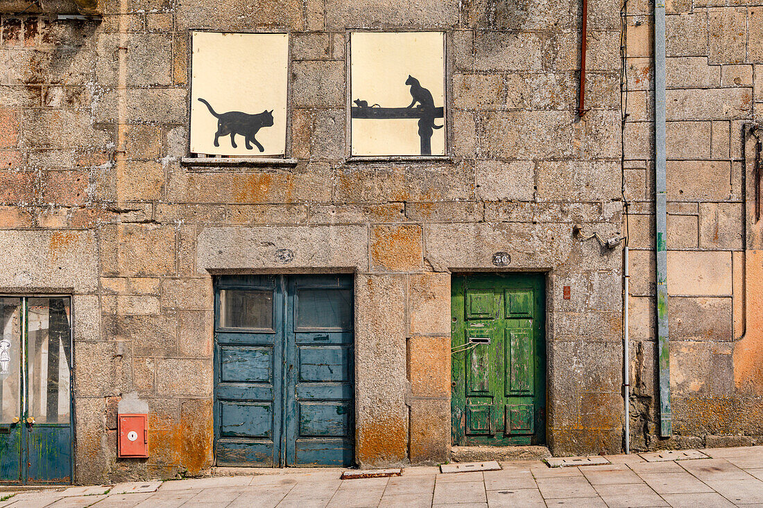 Fassade eines Hauses aus Stein mit künstlerisch alten und unterschiedlich farbigen Türen, Guarda, Portugal