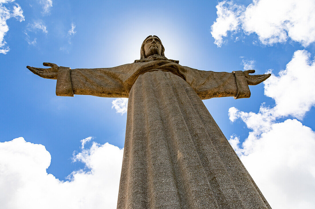 The statue of Christ Cristo-Rei as Christ the King seen from below against blue sky, Almada, Lisbon, Portugal