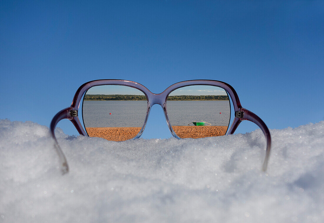 Strand und Seeufer in Reflexion in Sonnenbrillen auf dickem Schnee