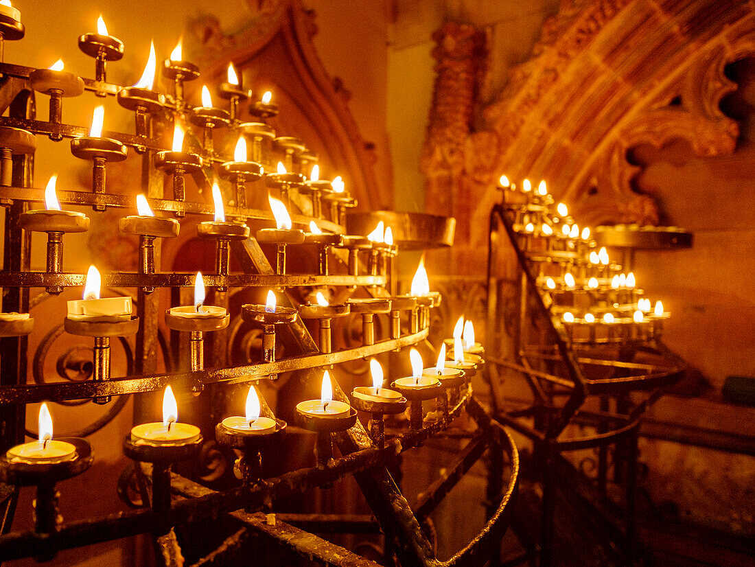 Lit candles in racks in a historic church, Edinburgh, UK
