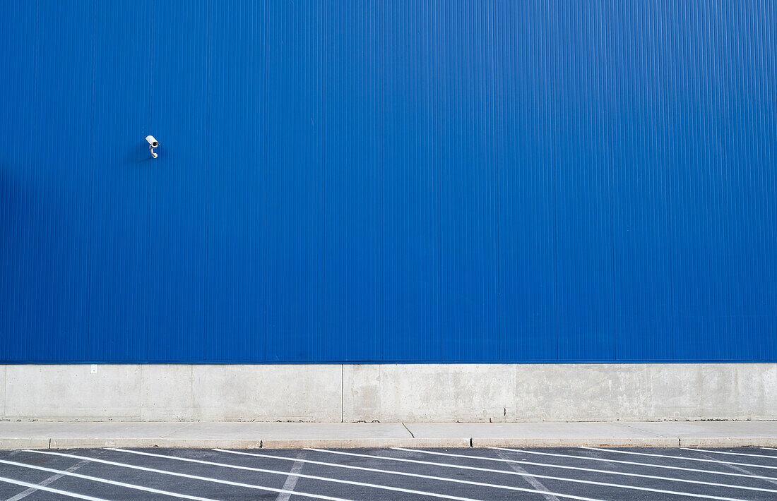 Surveillance camera on a blue exterior wall of warehouse or large windowless building, Philadelphia, USA