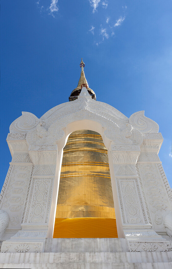 Gold painted chedi at Wat Suan Dok, white stone archway and tall tapered tower, Thailand