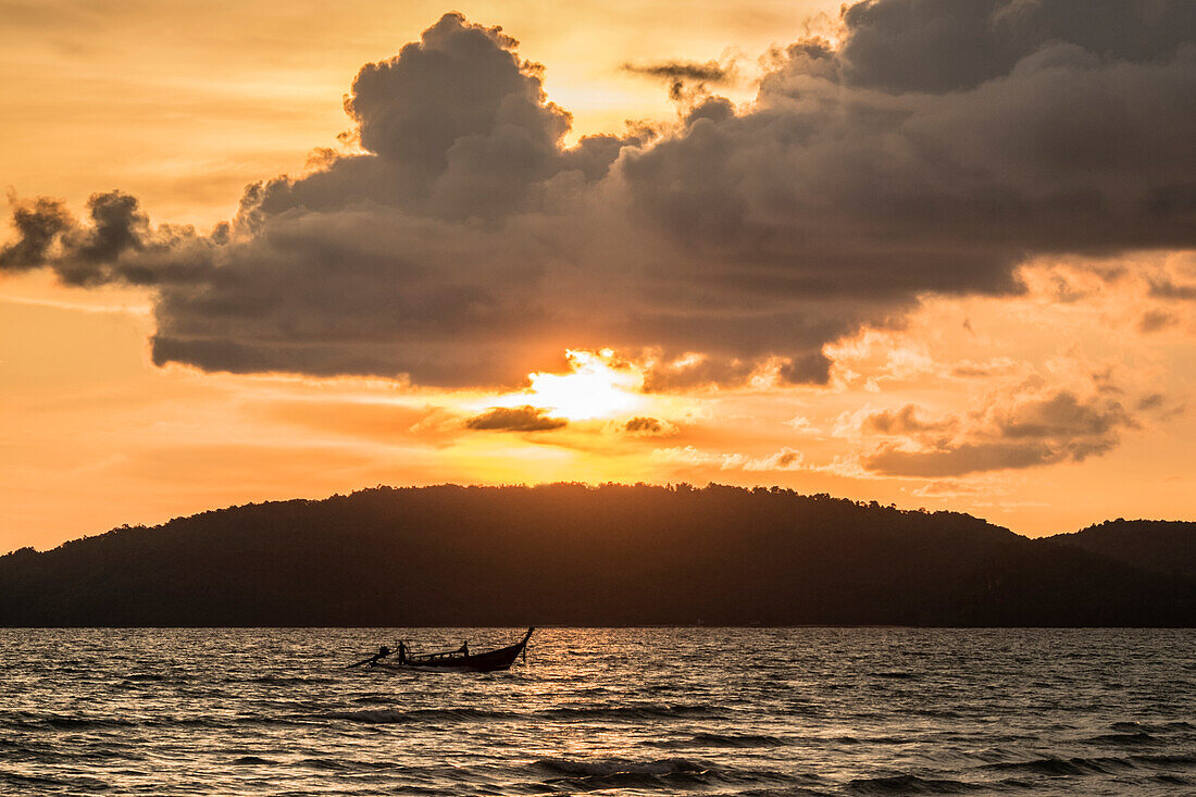 Sunset over wooded land with ocean in foreground, Thailand