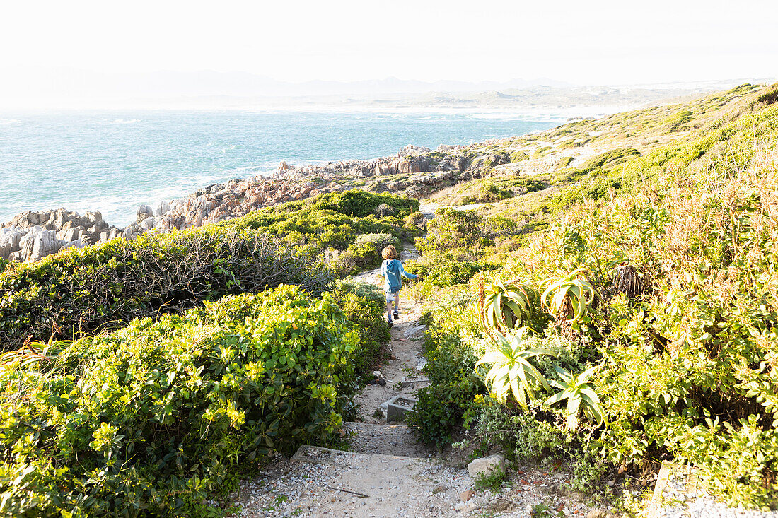 A boy running down the path to the beach at De Kelders, Western Cape, South Africa