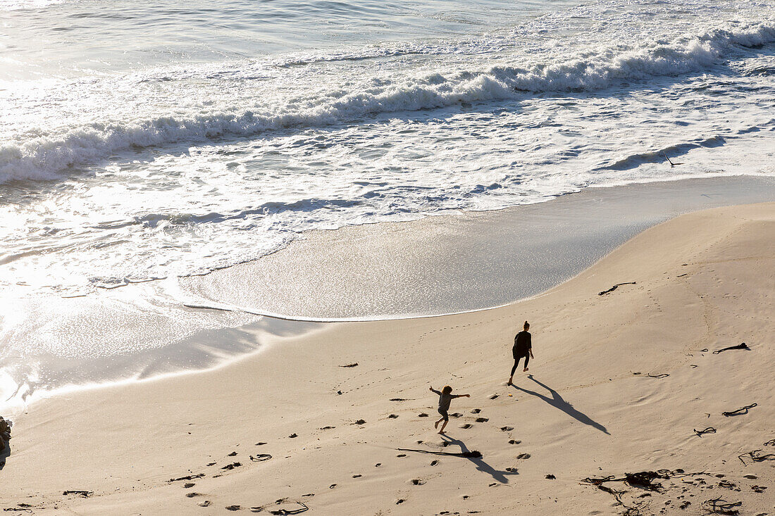Zwei Kinder laufen und hinterlassen Spuren im weichen Sand eines Strandes