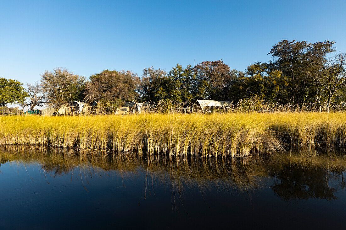 Kleine Gruppe von permanenten Safaricamp-Zelten an einer Wasserstraße, Okavango-Delta, Botswana, Afrika
