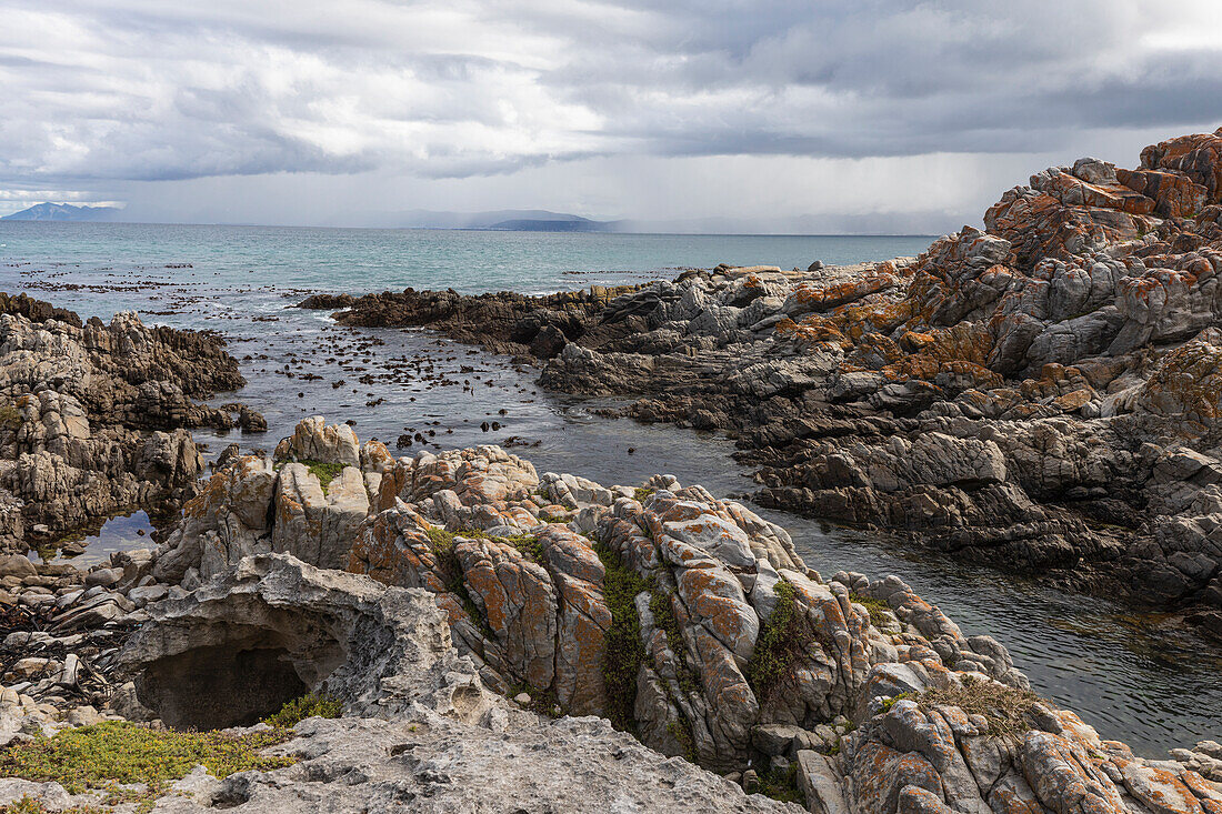 Rocky jagged coastline, eroded sandstone rock, view out to the ocean, De Kelders,South Africa