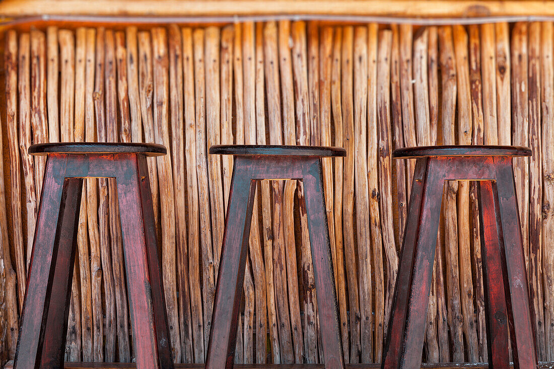 Three bar stools and bar on a beach