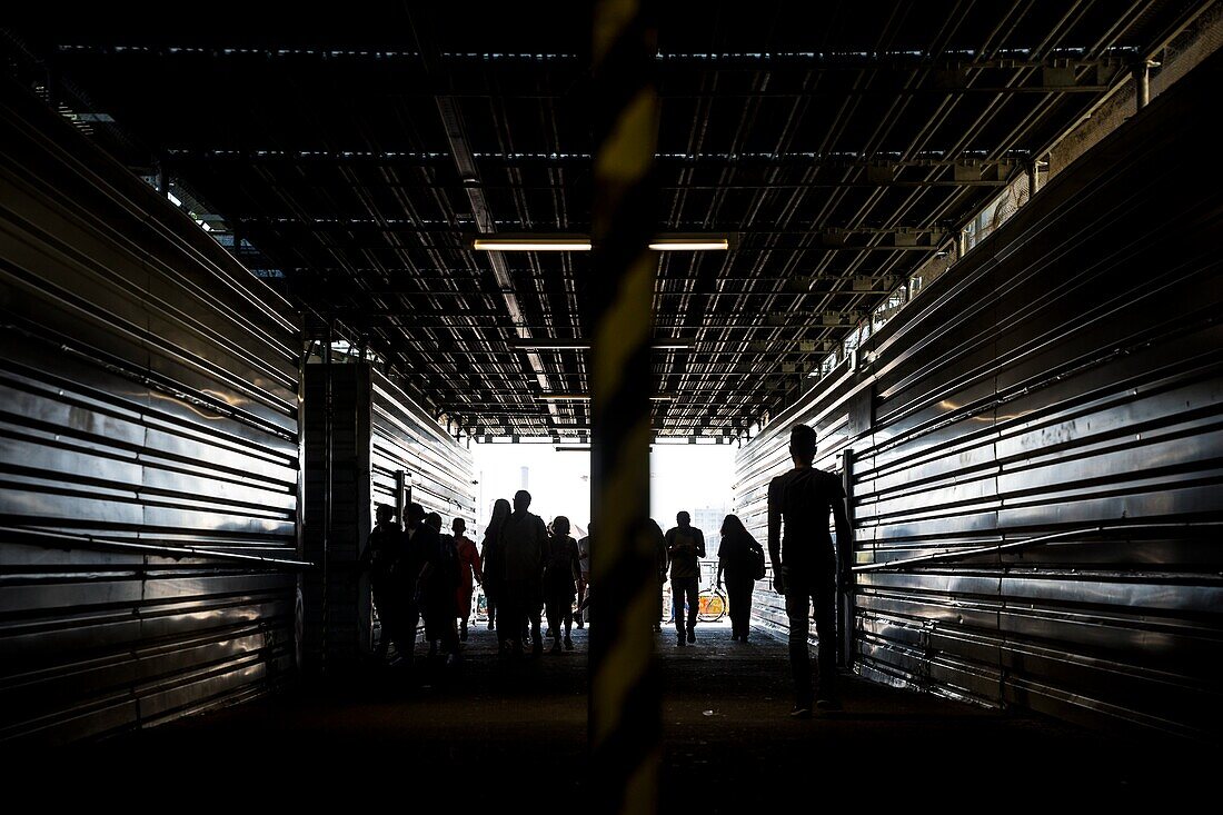 Silhouetted people in a tunnel at the entrance to the Warschauer Strasse SBahn station in Berlin,Germany.