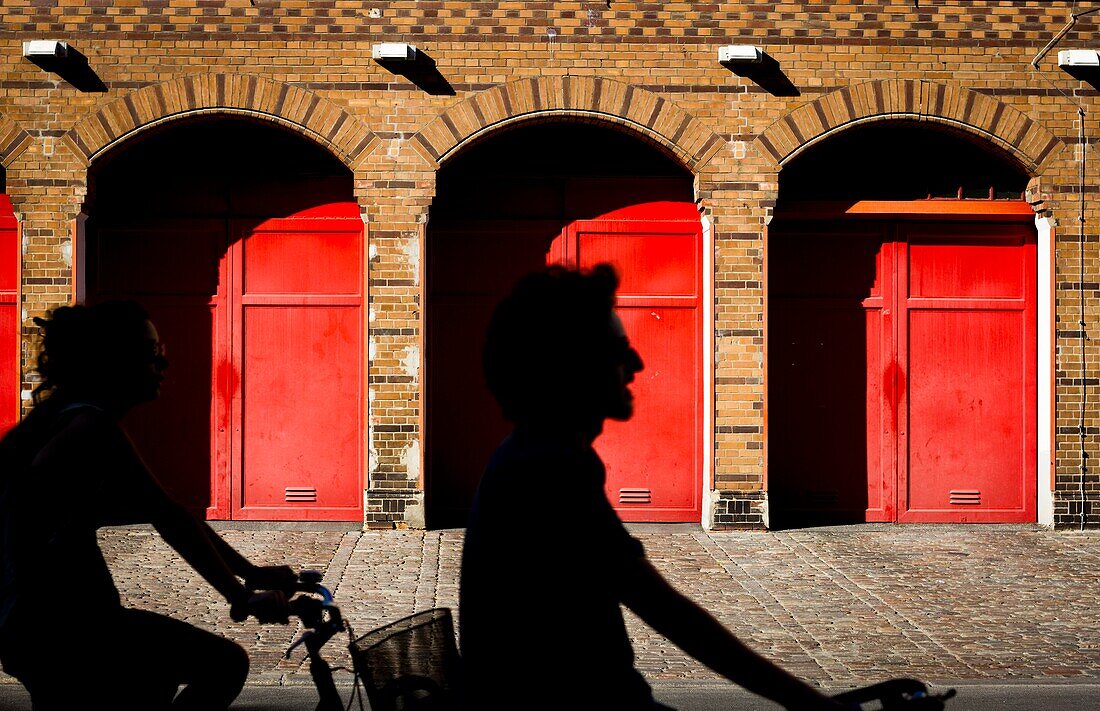 Radfahrer passieren rote Türen in Berlin, Deutschland.