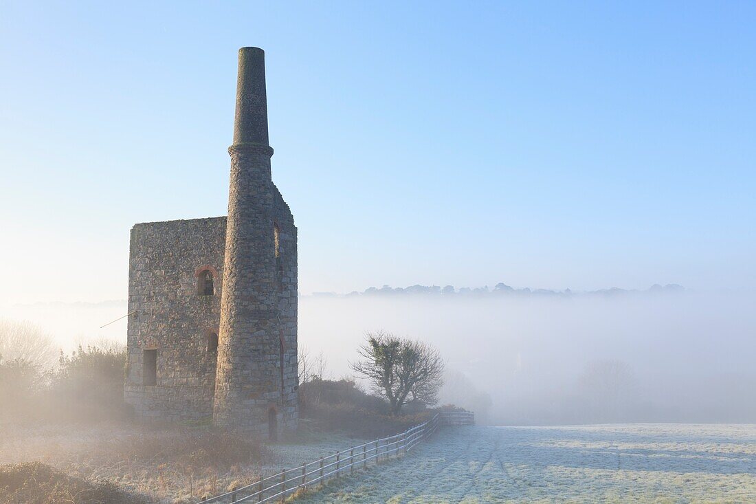Der Eingang zu den Maschinenhäusern in Wheal Bush, in der Nähe von Crofthandy in der Mitte von Cornwall, wurde an einem frostigen Morgen Ende Januar mit Nebel im Poldice-Tal in der Ferne aufgenommen.