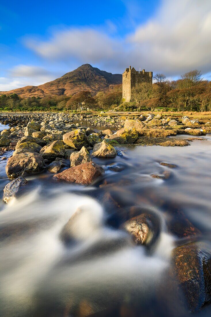 Moy Castle at the head of Loch Buie on the Isle of Mull illuminated by late afternoon sunlight. A long shutter speed was utilised to blur the movement in the foreground stream and the clouds.