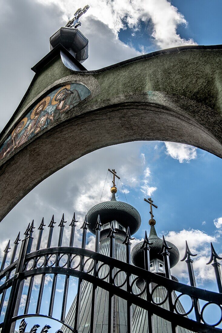 Hochwinkelansicht des geschlossenen Eisentors mit steinernem Torbogen, der christliche religiöse Ikonen vor Sabor Sviatoj Trojcy, orthodoxe Kirche, Polen darstellt.