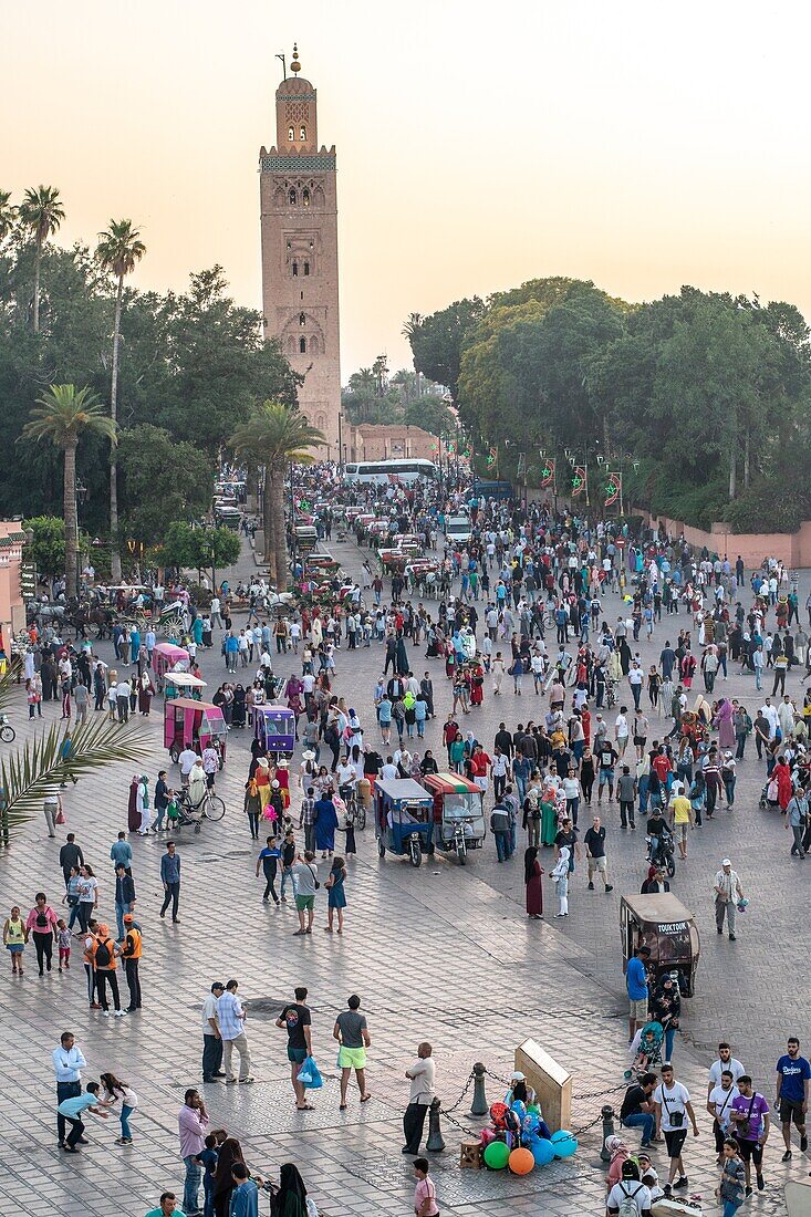 Die Koutoubia-Moschee erhebt sich in der Abenddämmerung über dem überfüllten Platz Jemaa el-Fnaa, Marrekech, Marokko.