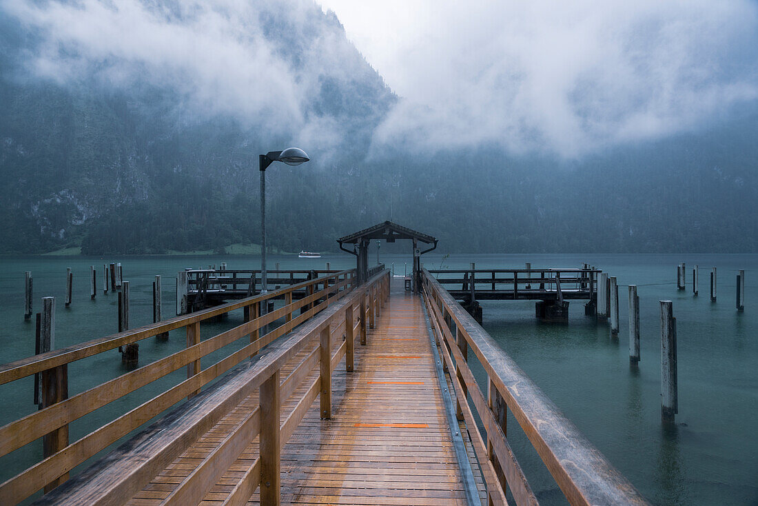 Germany, Bavaria, Pier on Koenigsee and cloud covered mountains