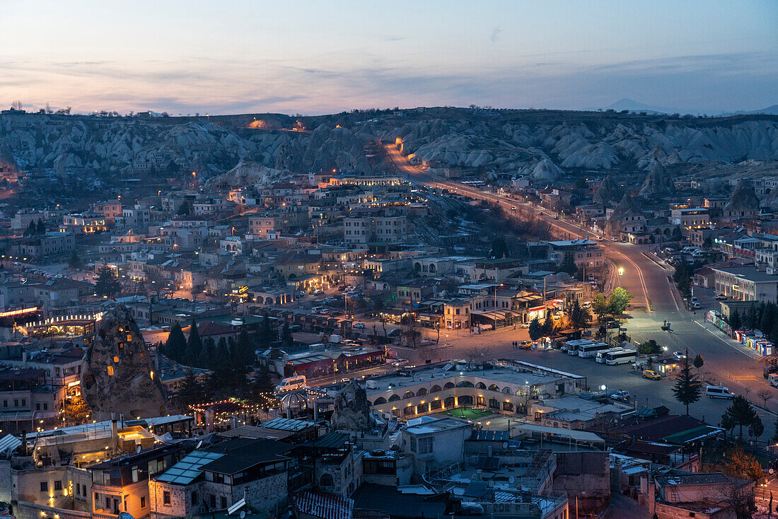 Turkey, Cappadocia, Goreme, Town illuminated at dusk and rock formations