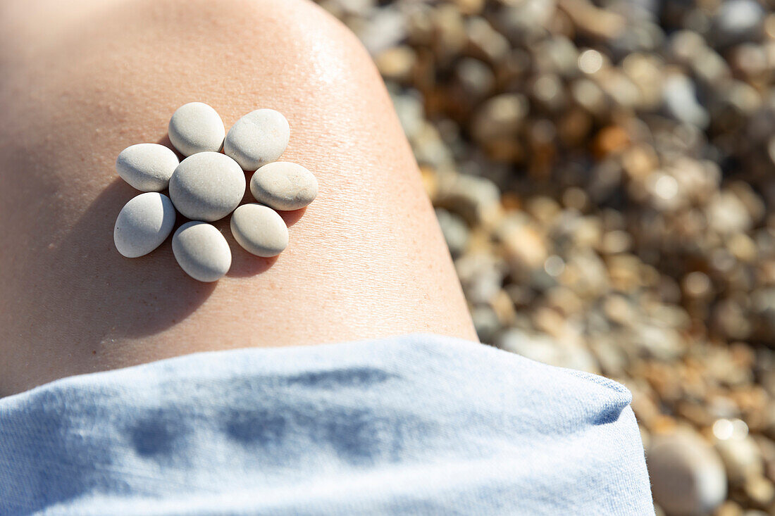 Pebbles arranged in flower shape on girls (4-5) leg