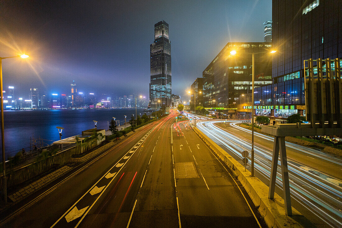Langzeitbelichtung des Verkehrs auf der Stadtstraße mit Wohngebäuden im Hintergrund, Hongkong