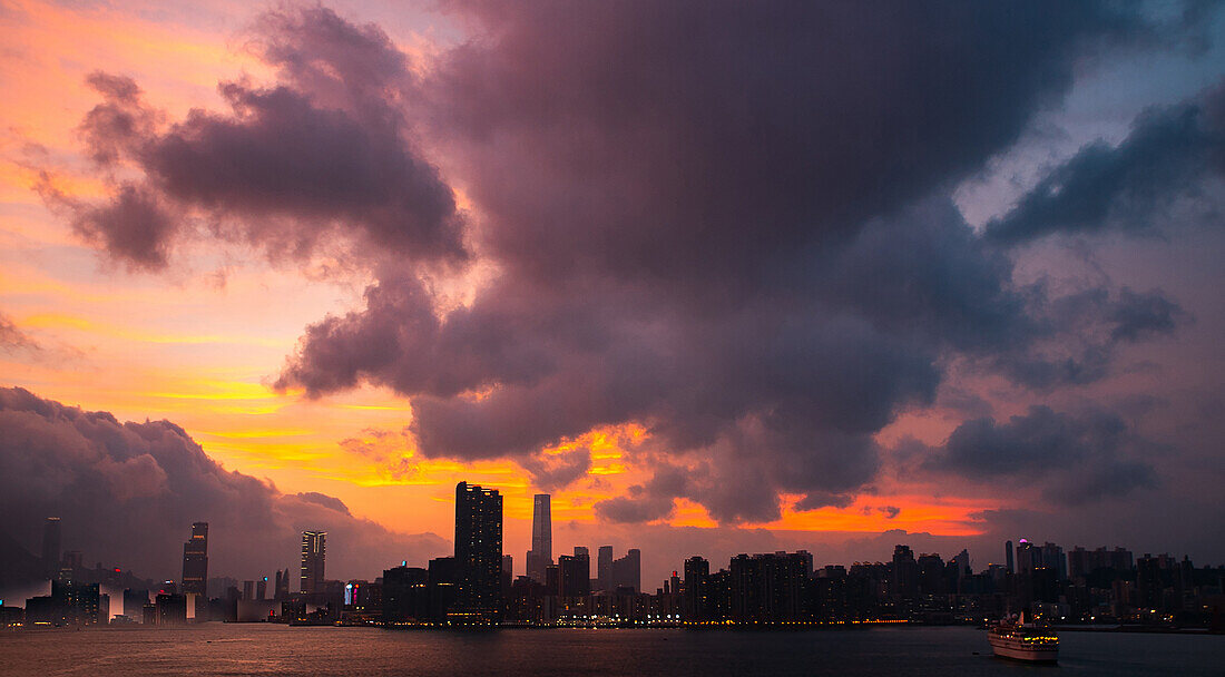 Blick auf die Skyline der Stadt unter den Gewitterwolken bei Sonnenuntergang, Hongkong, China