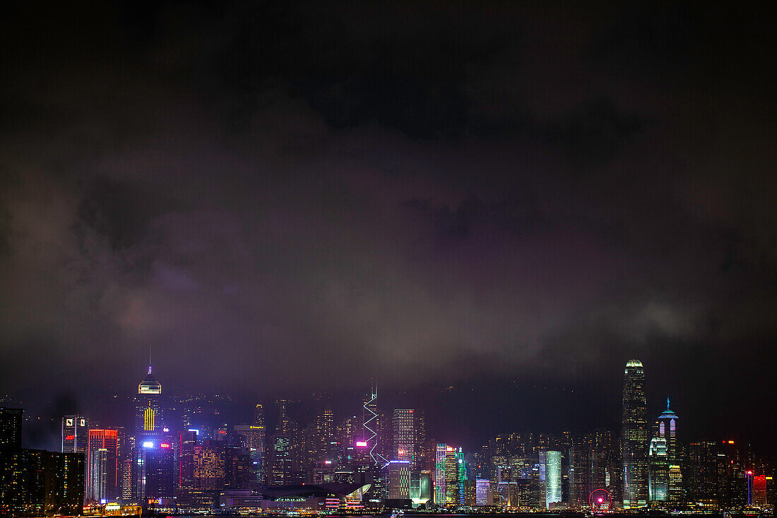 View of illuminated cityscape with skyscraper near Victoria Harbour in Hong Kong
