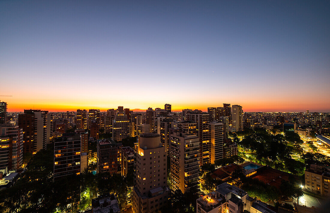Aerial view of crowded cityscape with high rise buildings at dusk