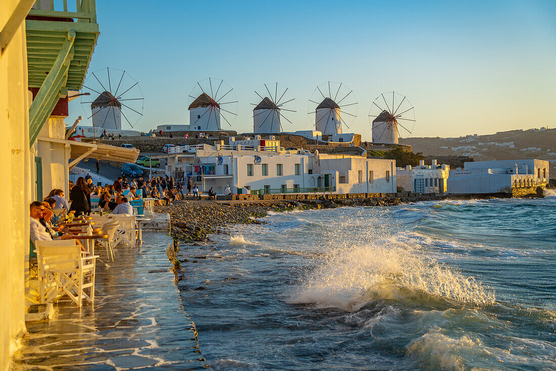 Blick auf die Windmühlen und brechende Wellen in Mykonos-Stadt bei Sonnenuntergang, Mykonos, Kykladen, griechische Inseln, Ägäis, Griechenland, Europa
