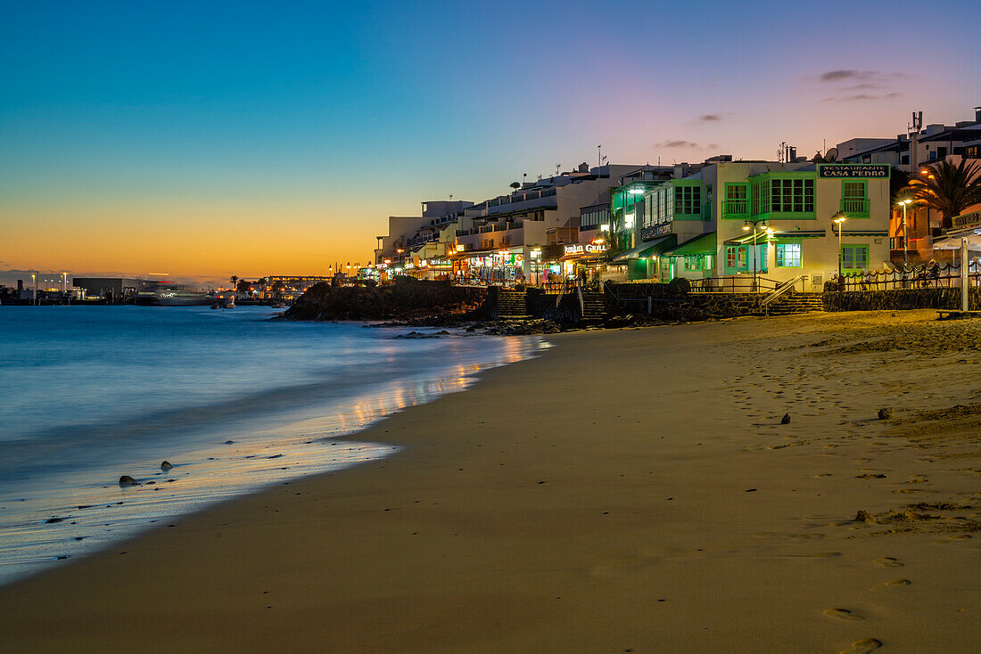 Blick auf Restaurants und Geschäfte mit Blick auf den Strand von Playa Blanca in der Abenddämmerung, Playa Blanca, Lanzarote, Kanarische Inseln, Spanien, Atlantik, Europa