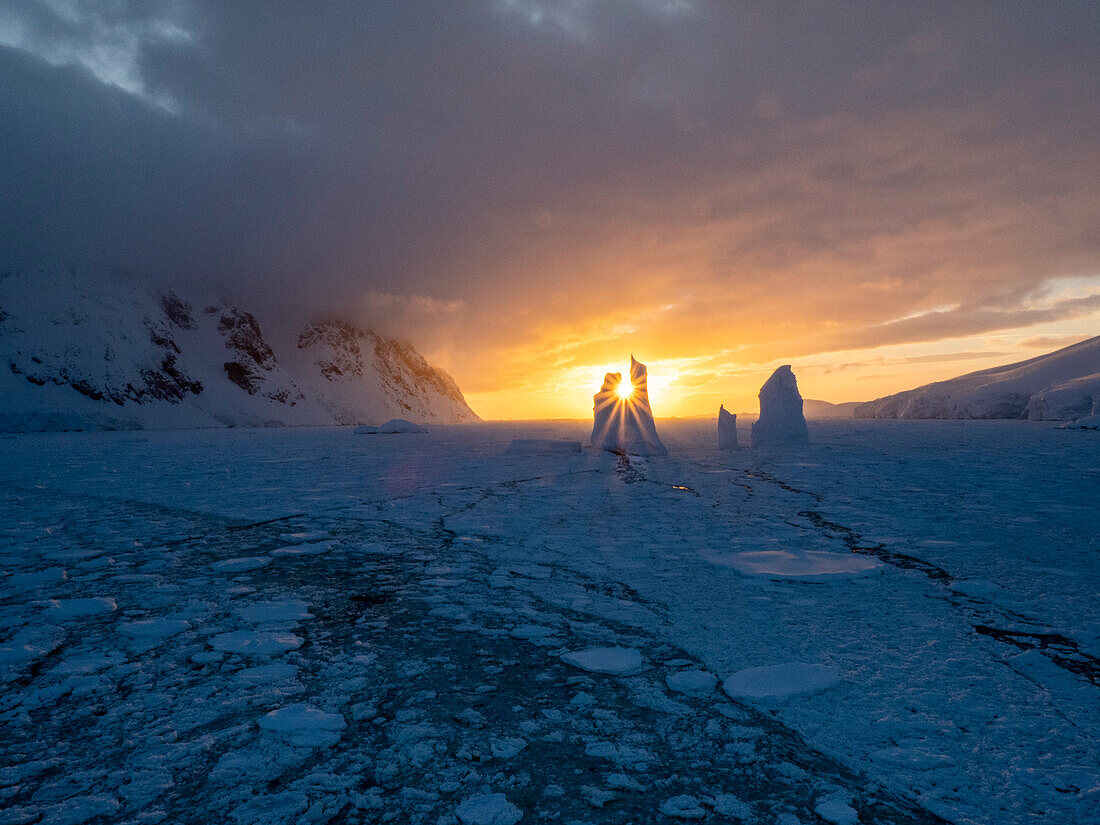 Sonnenuntergang über einem ungewöhnlichen Eisberg in der Nähe von Petermann Island, Antarktis, Polarregionen