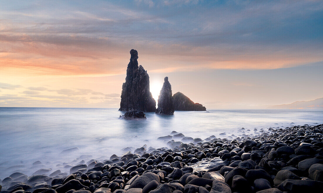 Waves crashing on volcanic stone beach and sea stacks of Ilheus da Rib and Ribeira da Janela at sunrise, Madeira island, Portugal, Atlantic, Europe