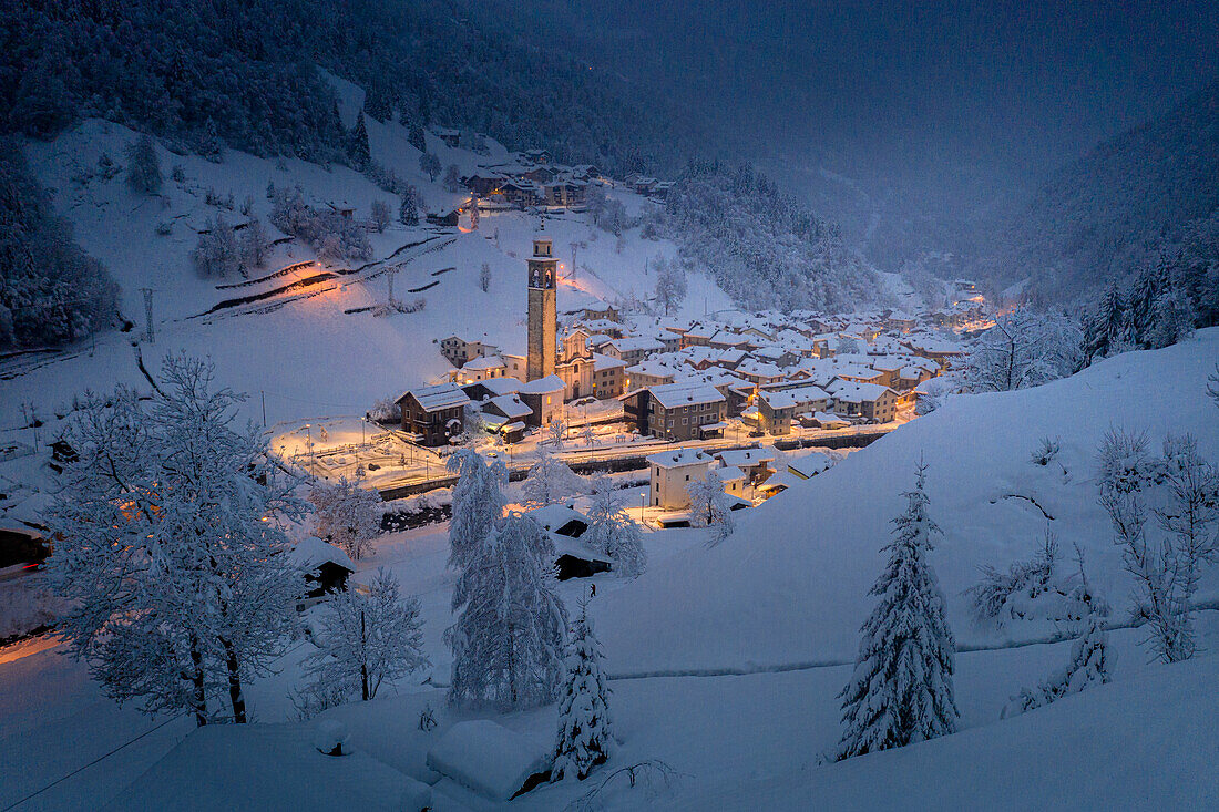 Winterdämmerung über dem beleuchteten Dorf im Tiefschnee, Gerola Alta, Valgerola, Orobische Alpen, Veltlin, Lombardei, Italien, Europa