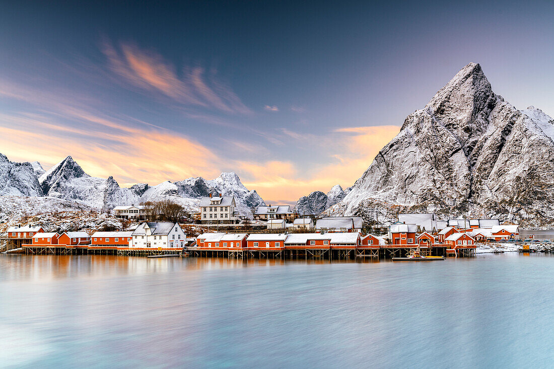 Winter sunset over snowcapped mountains and Sakrisoy village by the frozen sea, Reine, Nordland, Lofoten Islands, Norway, Scandinavia, Europe
